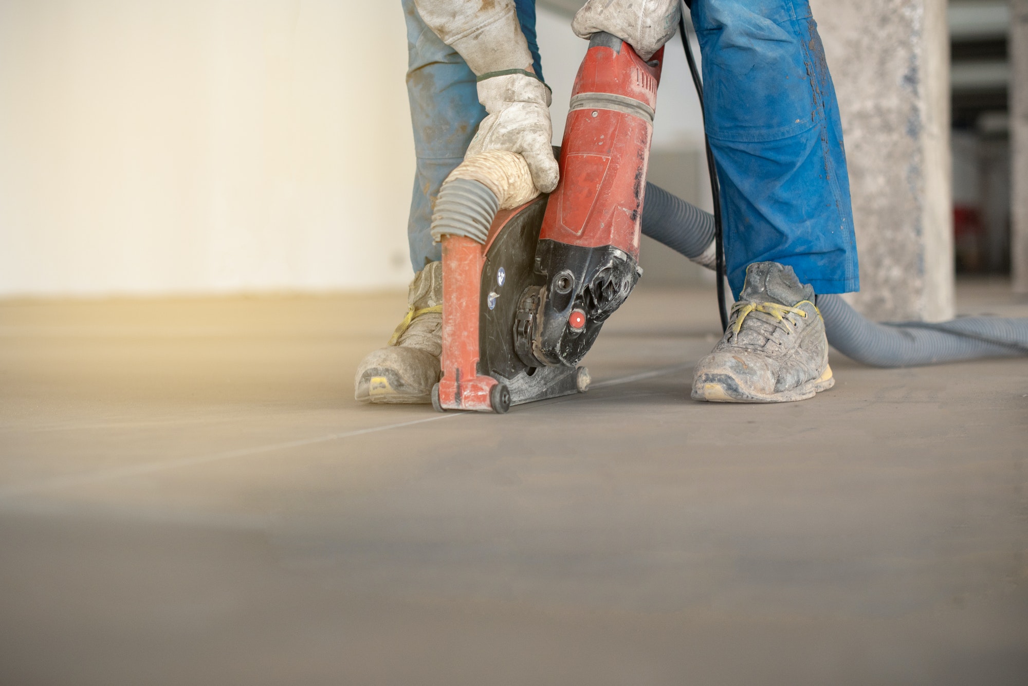 Worker working on the floor of an industrial building cutting the floor with a professional cutter.